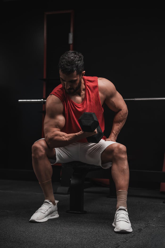 Male bodybuilder in gym lifting dumbbell, focusing on strength training.